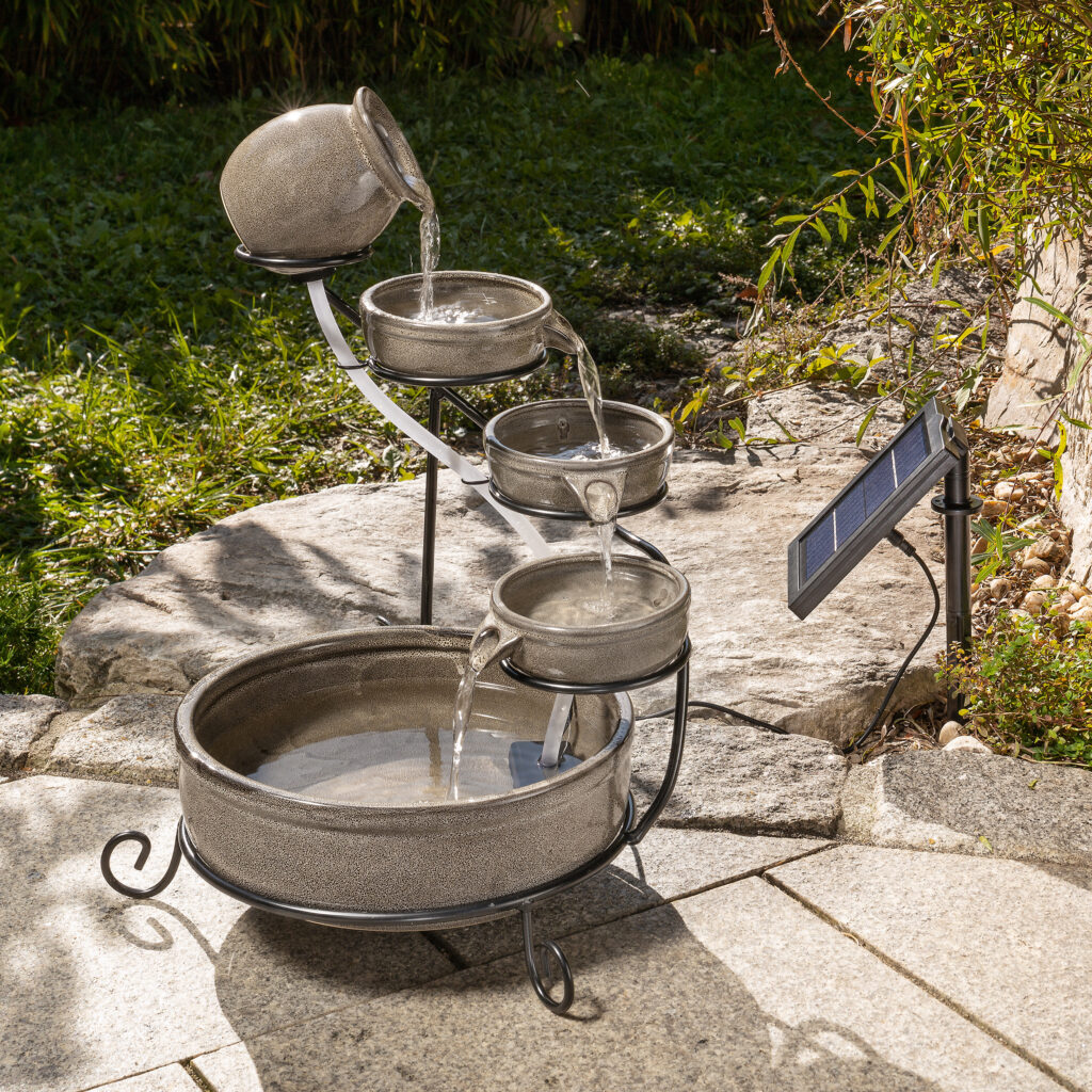 Solarbrunnen für den Balkon: Bild zeigt den Kaskadenbrunnen Firenze in grau, der auf einer Gartenterrasse steht